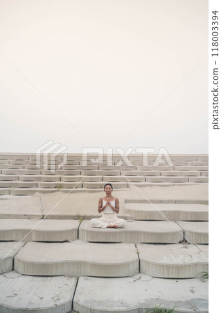 Young woman sitting on the beach and doing yoga Young woman sitting on the beach and doing yoga 118003394