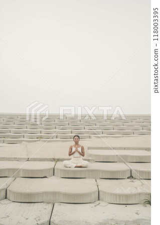 Young woman sitting on the beach and doing yoga Young woman sitting on the beach and doing yoga 118003395