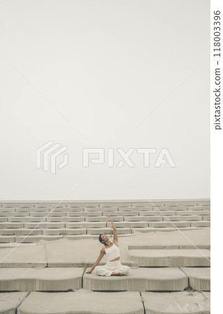 Young woman sitting on the beach and doing yoga 118003396