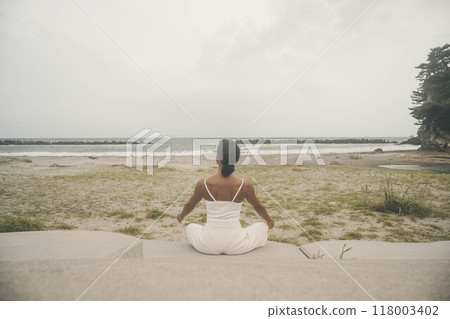 坐在海邊做瑜珈的年輕女子 坐在海邊做瑜珈的年輕女子 118003402