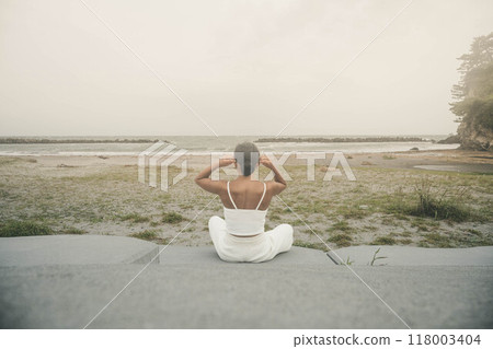 坐在海邊做瑜珈的年輕女子 118003404