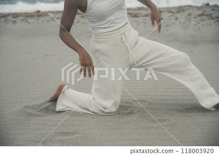 Young woman doing yoga on the beach 118003920