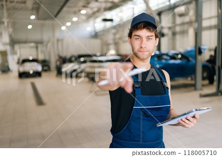 Confident automotive mechanic male pointing finger at camera looking with serious expression., choosing, inviting people,, holding digital tablet, at vehicle repair shop. Concept of auto maintenance. Confident automotive mechanic male pointing finger at camera looking with serious expression., choosing, inviting people,, holding digital tablet, at vehicle repair shop. Concept of auto maintenance. 118005710