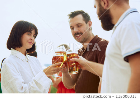 Group of friends clinking beer glasses, celebrating their meeting outdoor. Young people looks happy and cheerful. Concept of Friday mood. Group of friends clinking beer glasses, celebrating their meeting outdoor. Young people looks happy and cheerful. Concept of Friday mood. 118006315