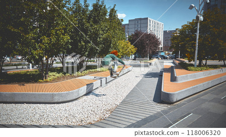 Red-haired curly young man in green outfit, skater in motion, skateboarding outdoors in public park, showing skills and freedom vibe 118006320