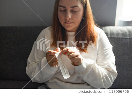 Caucasian woman holds nasal swab and puts into nose for COVID-19 self test at home 118006706
