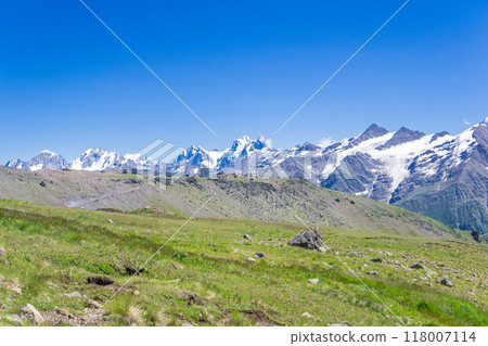mountain landscape with alpine meadow, observatory in the distance and mountain peaks in the background 118007114