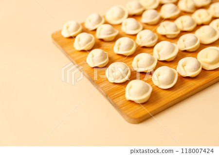 Close-up semi-finished raw dumplings lie neatly on a wooden board, copy space. 118007424