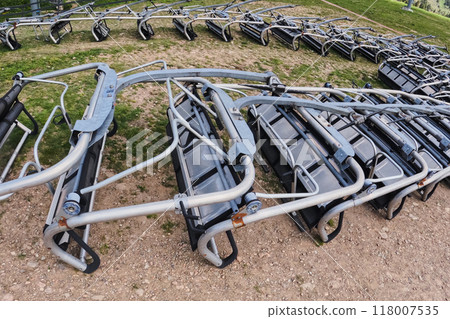 Many ski lift chairs lie on the slope for maintenance before the ski season, patiently awaiting the arrival of winter. 118007535