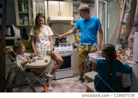 A loving family is happily enjoying quality time together in their cozy kitchen, showcasing warmth and connection 118007536