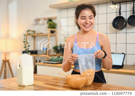 Portrait of young fitness woman in sportswear preparing breakfast on kitchen counter 118007779