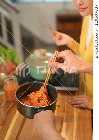Young couple eating freshly cooked instant noodles on the wooden countertop Young couple eating freshly cooked instant noodles on the wooden countertop 118007837