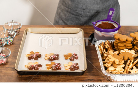 Preparing star-shaped cookies, half-dipped in chocolate, accented with peppermint chocolate chips for the holidays. 118008043