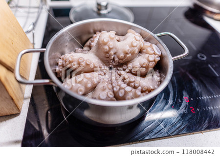 From above of whole raw octopus boiling in pot on modern black induction cooker 118008442
