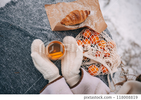 Warm drink and croissant with oranges on a cozy blanket in winter surroundings 118008819