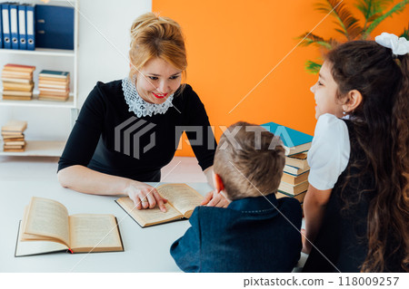Woman teacher and children schoolchildren in the library with books Woman teacher and children schoolchildren in the library with books 118009257