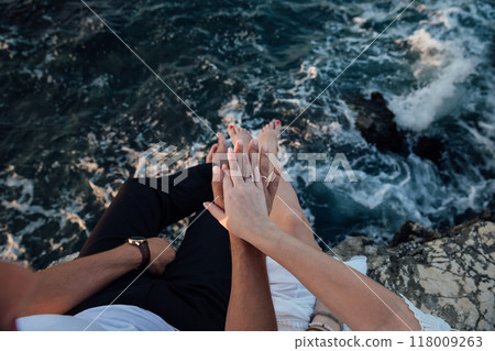 Male and female hands together on a cliff in front of the sea 118009263