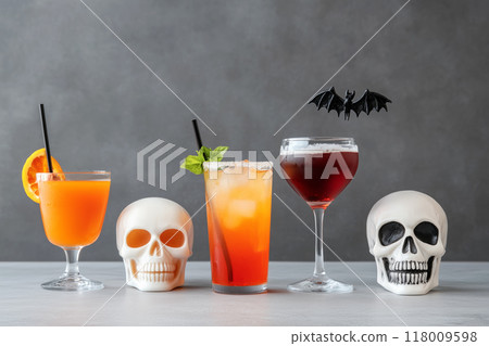 Variety of Halloween-themed cocktails served in skull-shaped and traditional glasses, adorned with orange slices and bat stirrers on concrete background. Concept for festive Halloween celebrations Variety of Halloween-themed cocktails served in skull-shaped and traditional glasses, adorned with orange slices and bat stirrers on concrete background. Concept for festive Halloween celebrations 118009598