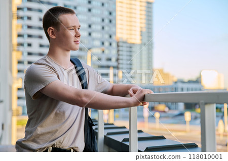 Portrait of young teenage guy, outdoors, modern skyscrapers background Portrait of young teenage guy, outdoors, modern skyscrapers background 118010001
