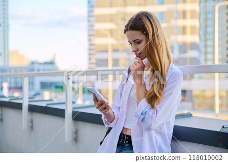 Young female using smartphone, modern city background 118010002