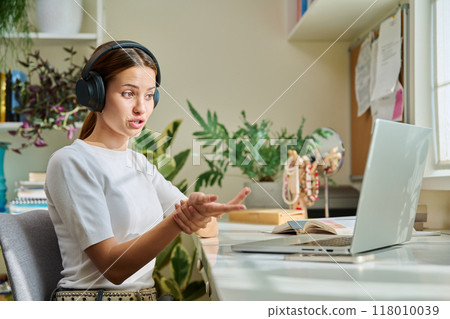 Girl teenage student in headphones having video chat online on computer 118010039
