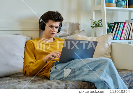 Young guy 19-20 years old in headphones using laptop, talking on video call 118010264