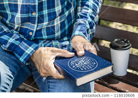 Koran in the hands of a modern Muslim on the street in the park. Religious Islamic culture and the holy book. 118010606