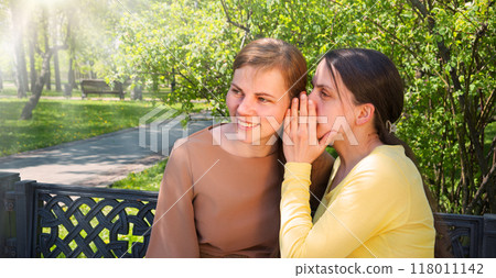Two girls gossip in the park Two girls gossip in the park 118011142