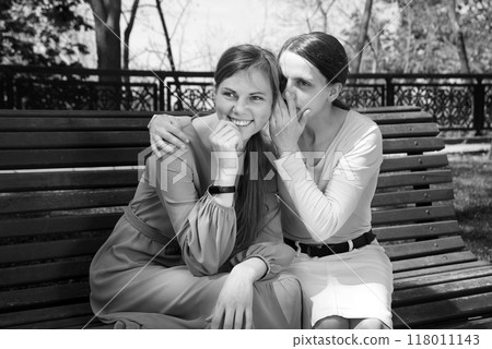 Two girls gossip in the park Two girls gossip in the park 118011143