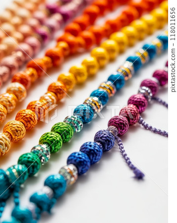 Intricately crafted bracelets in a spectrum of colors are arranged neatly on a light surface, highlighting their detailed patterns and textures. Each bracelet showcases unique craftsmanship 118011656
