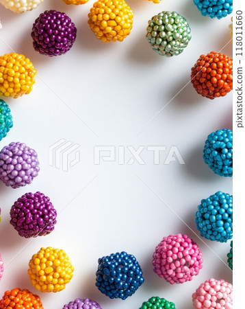 A variety of colorful round candies are creatively arranged in a circular pattern on a plain background, showcasing their vibrant hues and inviting appearance 118011660
