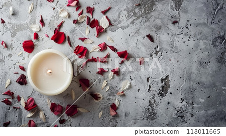 A serene white candle surrounded by rose petals on a textured gray surface 118011665