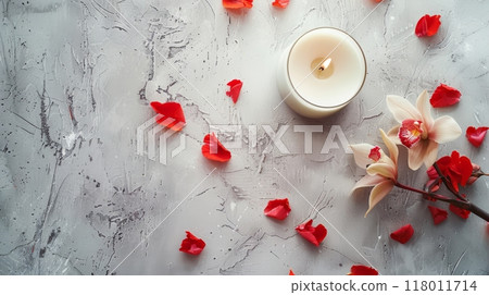 Relaxing candle and flower arrangement with petals on a textured gray surface 118011714