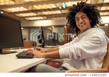 Man researching for college project via computer while sitting in library Man researching for college project via computer while sitting in library 118012204