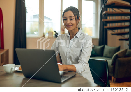 Smiling cute young woman sitting at the laptop Smiling cute young woman sitting at the laptop 118012242