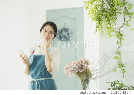 A woman in an apron looking at her smartphone A woman in an apron looking at her smartphone 118014234