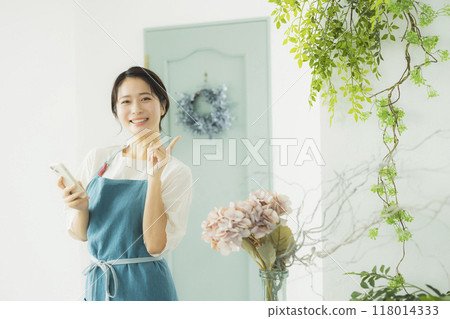 A woman in an apron looking at her smartphone A woman in an apron looking at her smartphone 118014333