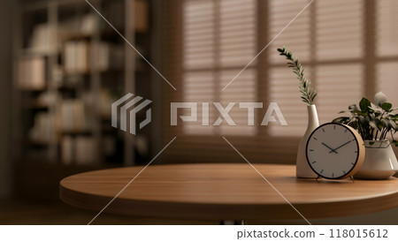 A round wooden table featuring an alarm clock, decorative plants, and a copy space. 118015612