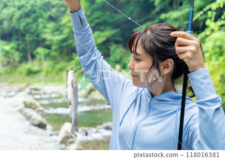 A woman fishing in a mountain stream A woman enjoying fishing A woman fishing in a mountain stream A woman enjoying fishing 118016381
