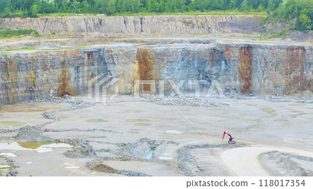 Aerial View of Excavator in Open-Pit Quarry with Stratified Rock Walls Aerial View of Excavator in Open-Pit Quarry with Stratified Rock Walls 118017354