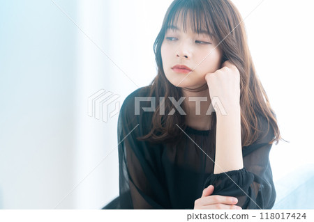 Young woman doing skin care by the window in the living room 118017424