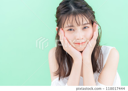 Young woman doing skin care on green background 118017444