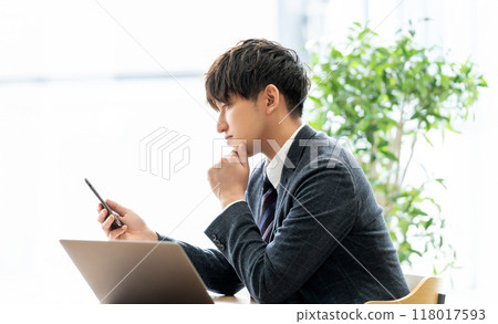 Male businessman looking at smartphone and thinking 118017593