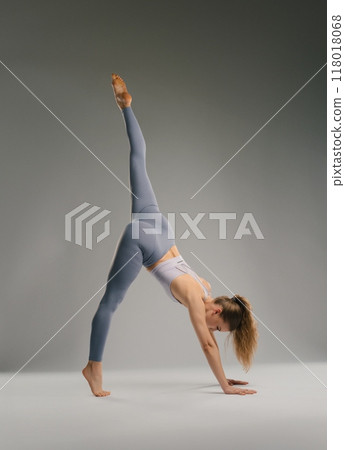 Woman practicing yoga in a stylish pose in a minimalistic studio setting 118018068