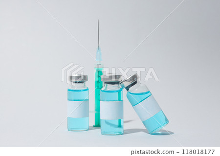 Glass medical bottles with vaccine and syringe on light background Glass medical bottles with vaccine and syringe on light background 118018177