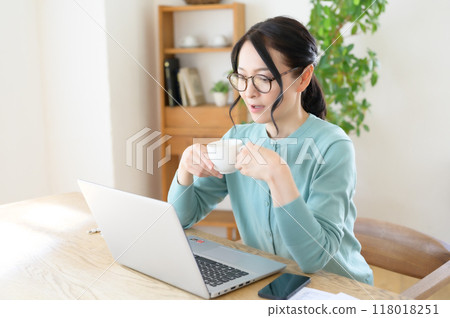 一位中年婦女手裡拿著咖啡在電腦前工作 一位中年婦女手裡拿著咖啡在電腦前工作 118018251