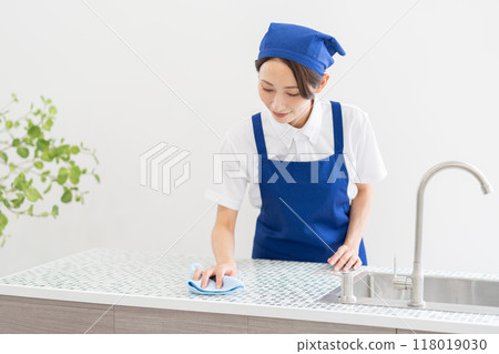 A woman from a housekeeping service cleaning the kitchen A woman from a housekeeping service cleaning the kitchen 118019030