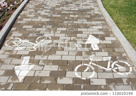 A brick walkway adorned with bicycle and arrow designs, enhancing the urban design with a unique twist. The combination of wood and brickwork creates a rustic yet modern flooring experience A brick walkway adorned with bicycle and arrow designs, enhancing the urban design with a unique twist. The combination of wood and brickwork creates a rustic yet modern flooring experience 118020199