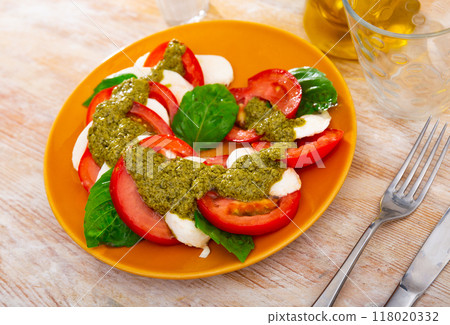 Caprese with basil leaves and pesto sauce on table 118020332