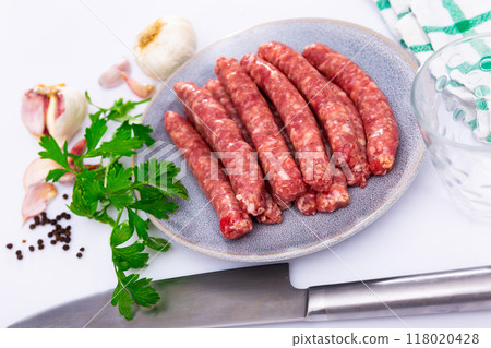 Plate of raw longaniza wit greens, garlic and spices prepared for cooking 118020428